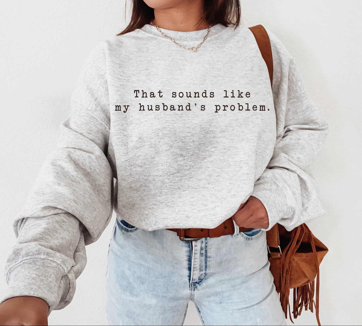Person wearing a gray sweatshirt with text 'That sounds like my husband's problem' on a white background
