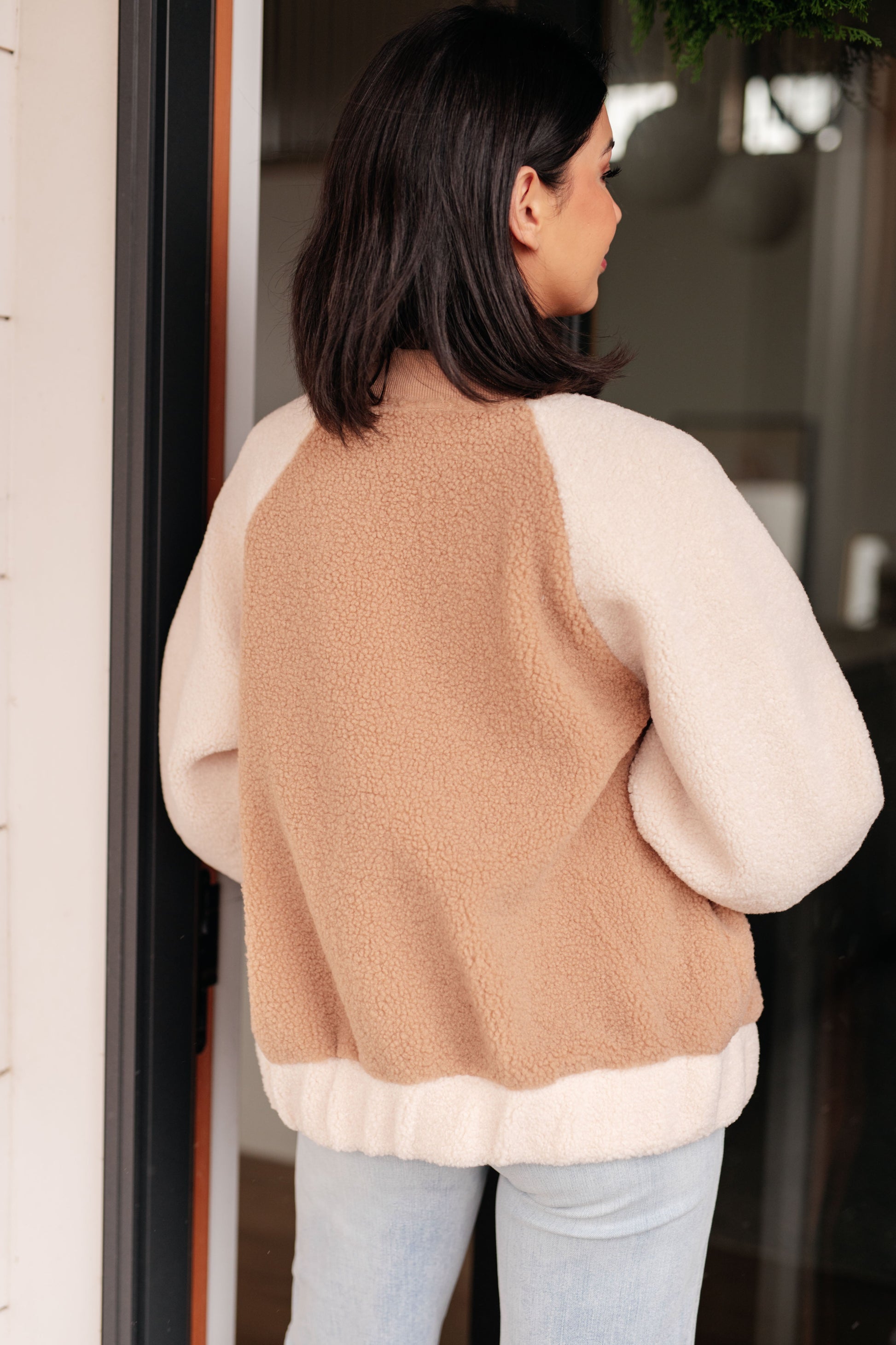 Person wearing a beige and white sweater with a neutral background