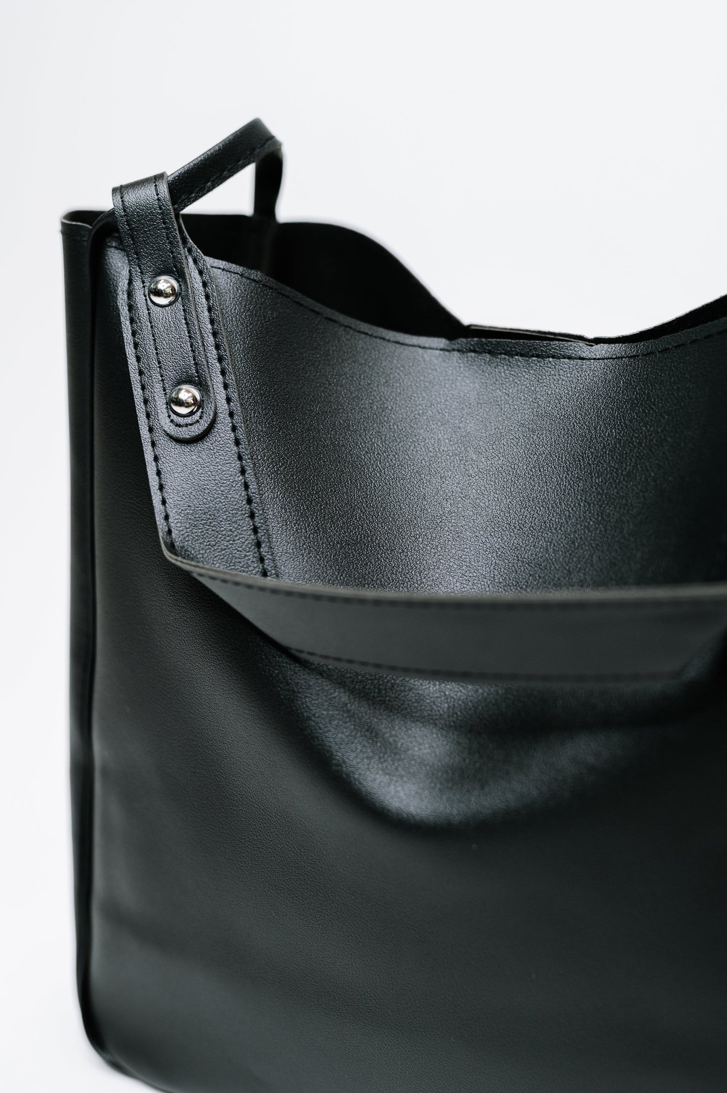 Black leather handbag with a strap on a white background
