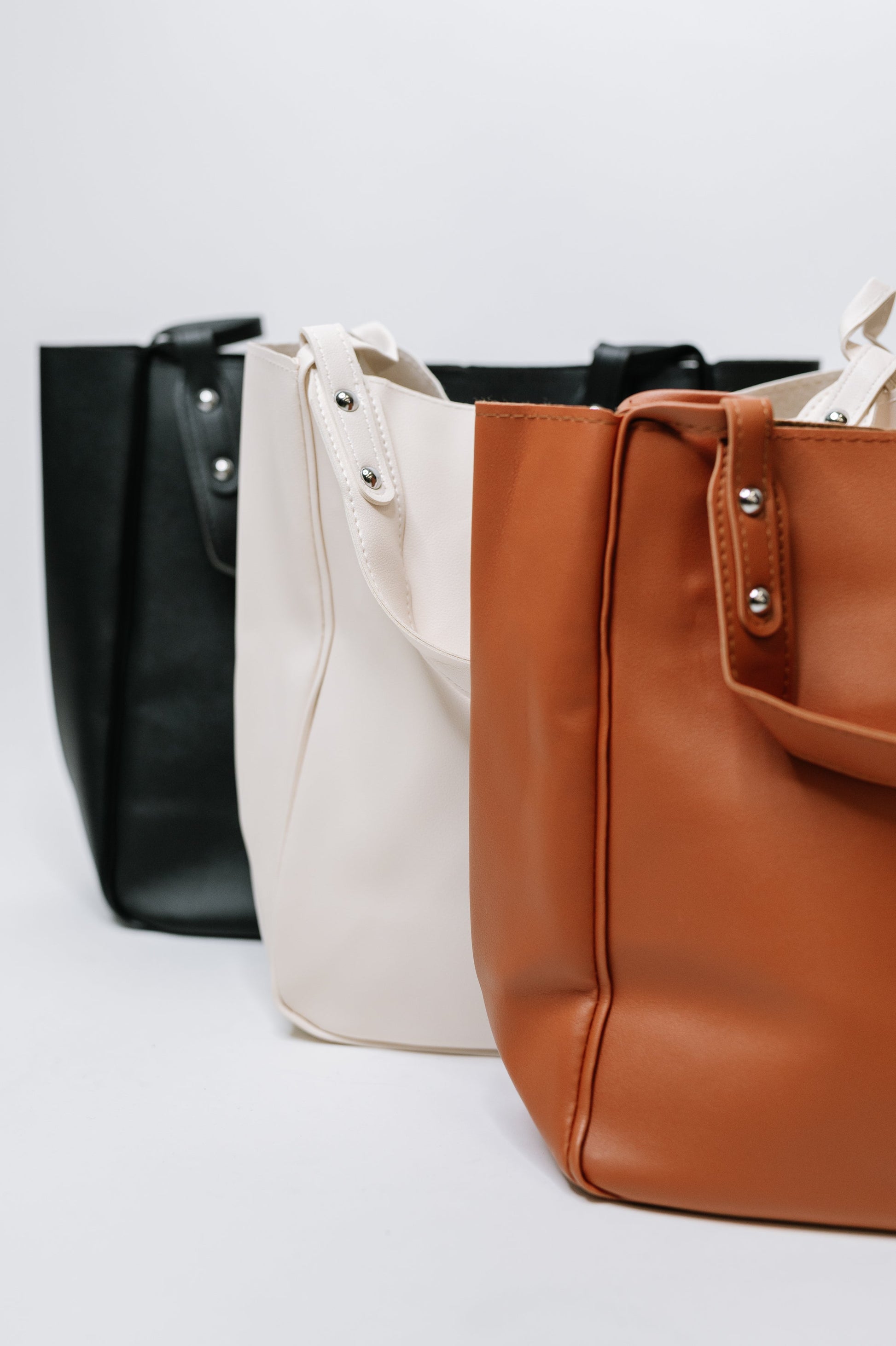 Three bags in black, white, and brown on a light gray background