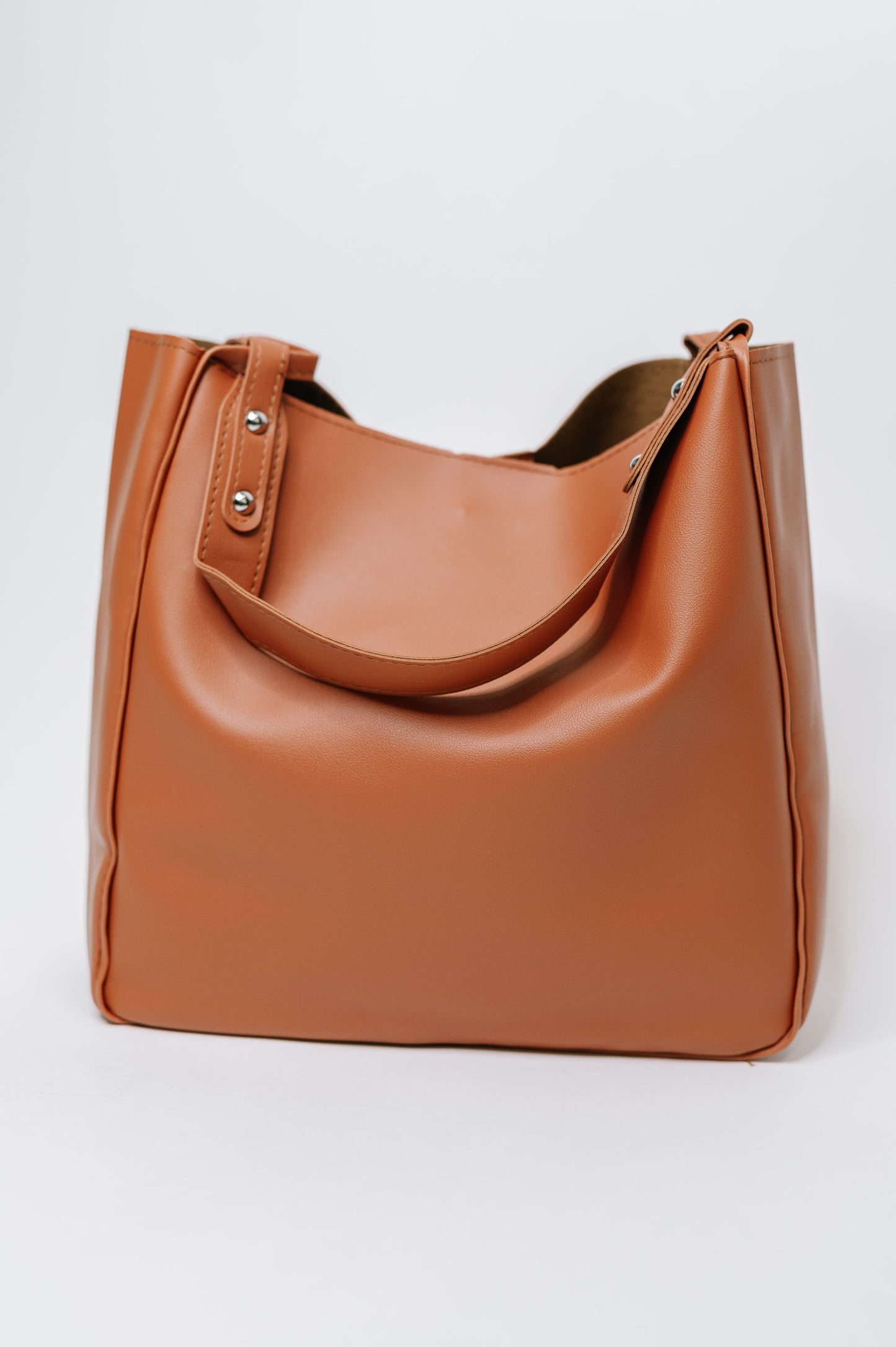 Brown leather tote bag on a light gray background