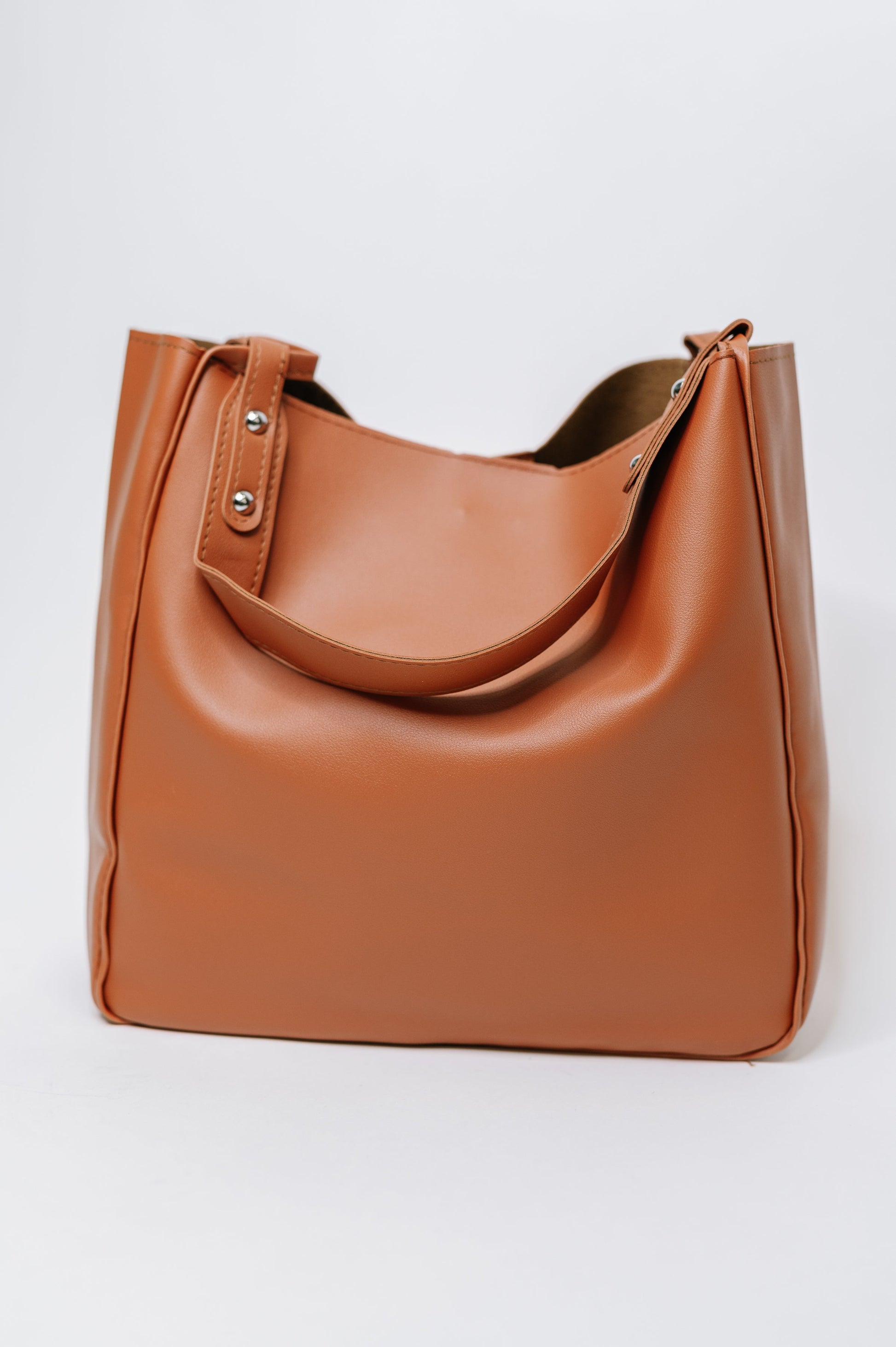 Brown leather tote bag on a light gray background