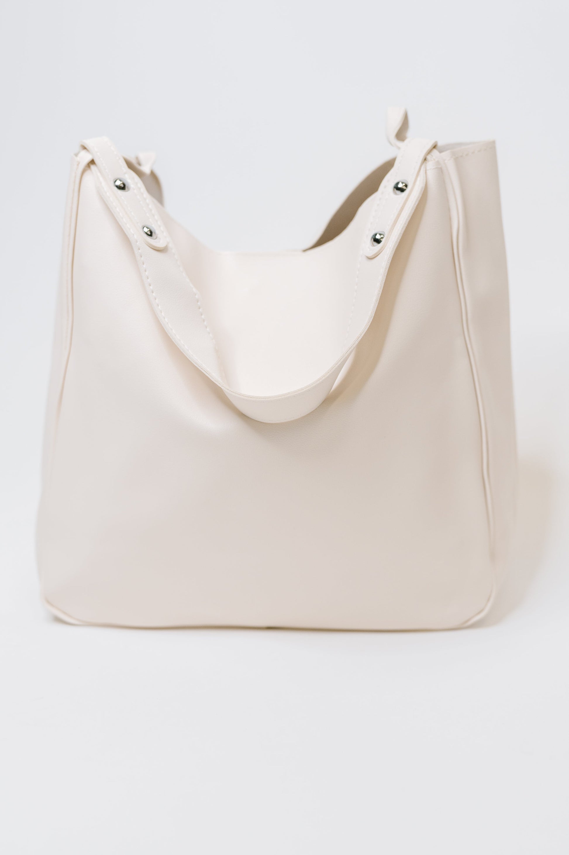 Beige tote bag with studded details on a white background