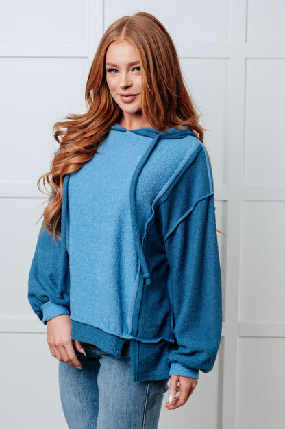 Woman wearing a blue hoodie against a white tiled wall