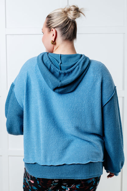 Person wearing a blue hoodie with a white tiled wall background