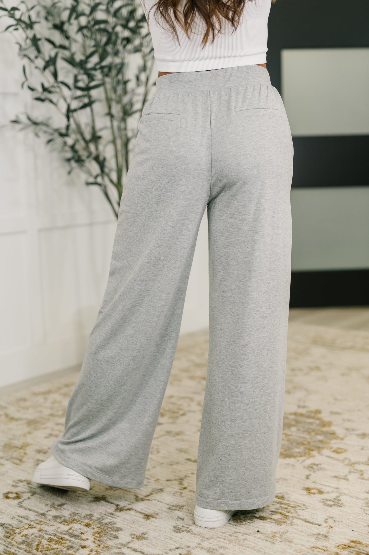 Person wearing gray wide-leg pants with a white top in an indoor setting.
