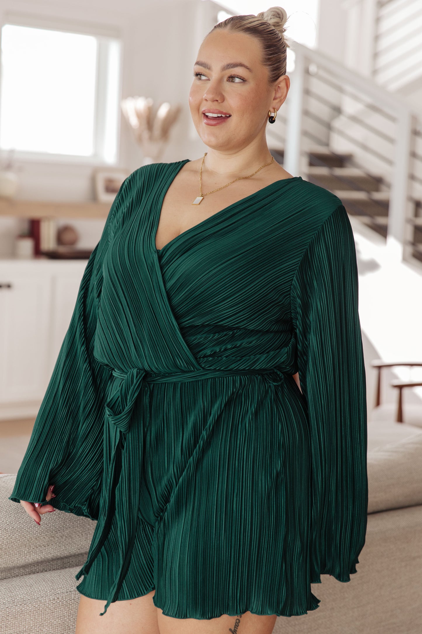 Woman wearing a green pleated dress in a home setting