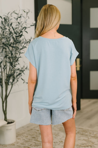 Person wearing a light blue oversized t-shirt and gray shorts in an indoor setting.