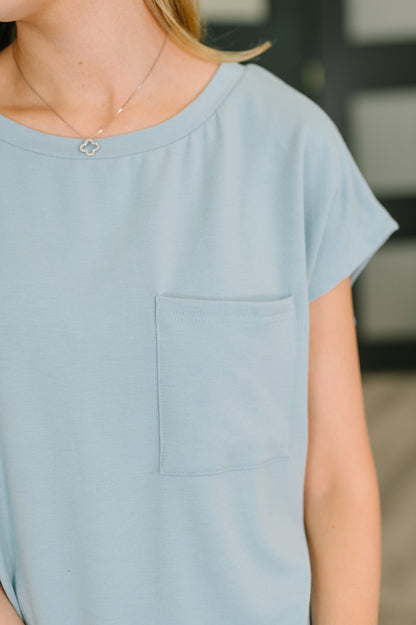 Light blue short-sleeve top with a pocket on a blurred background