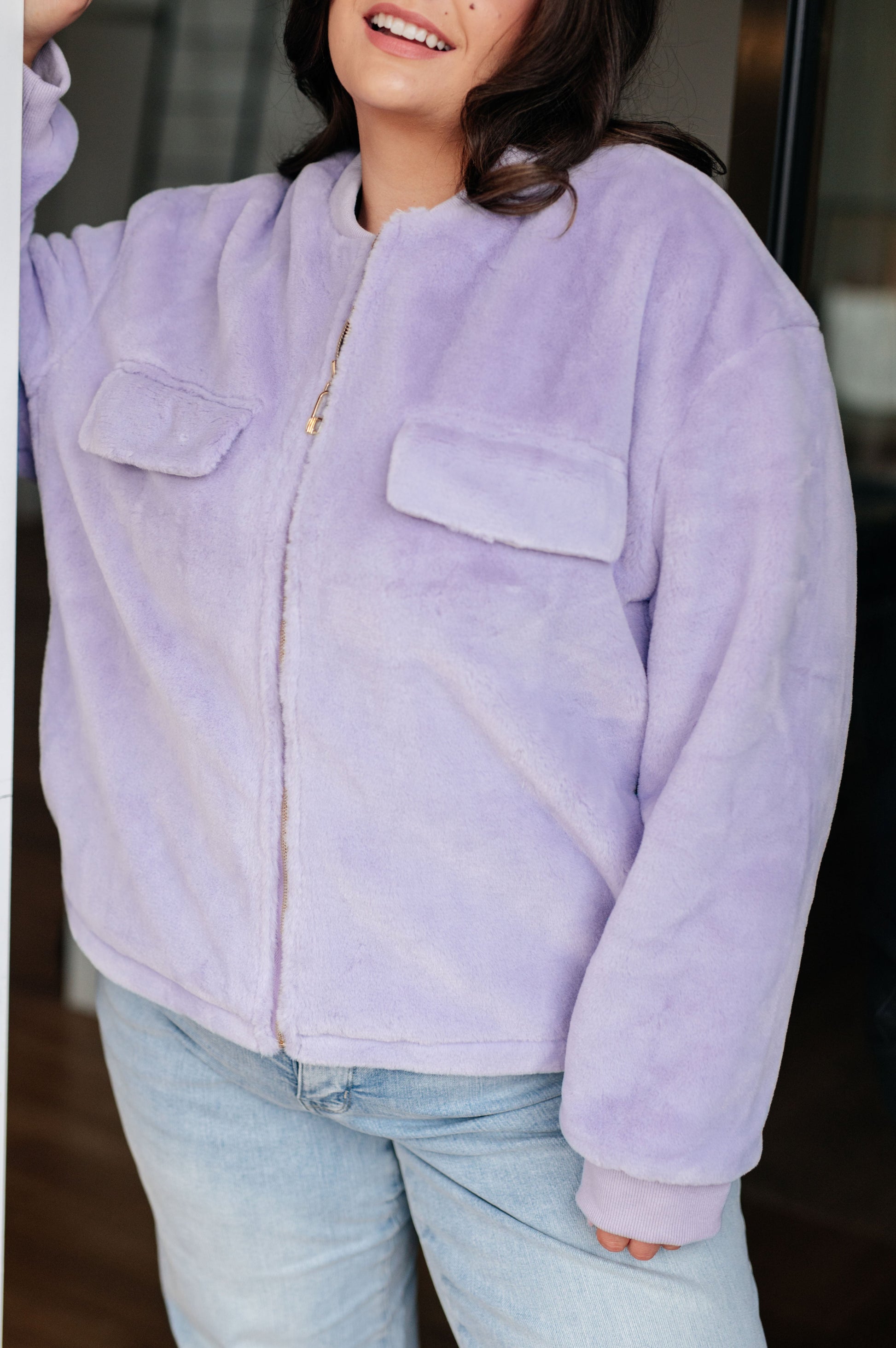 Person wearing a light purple fleece jacket with a blurred background