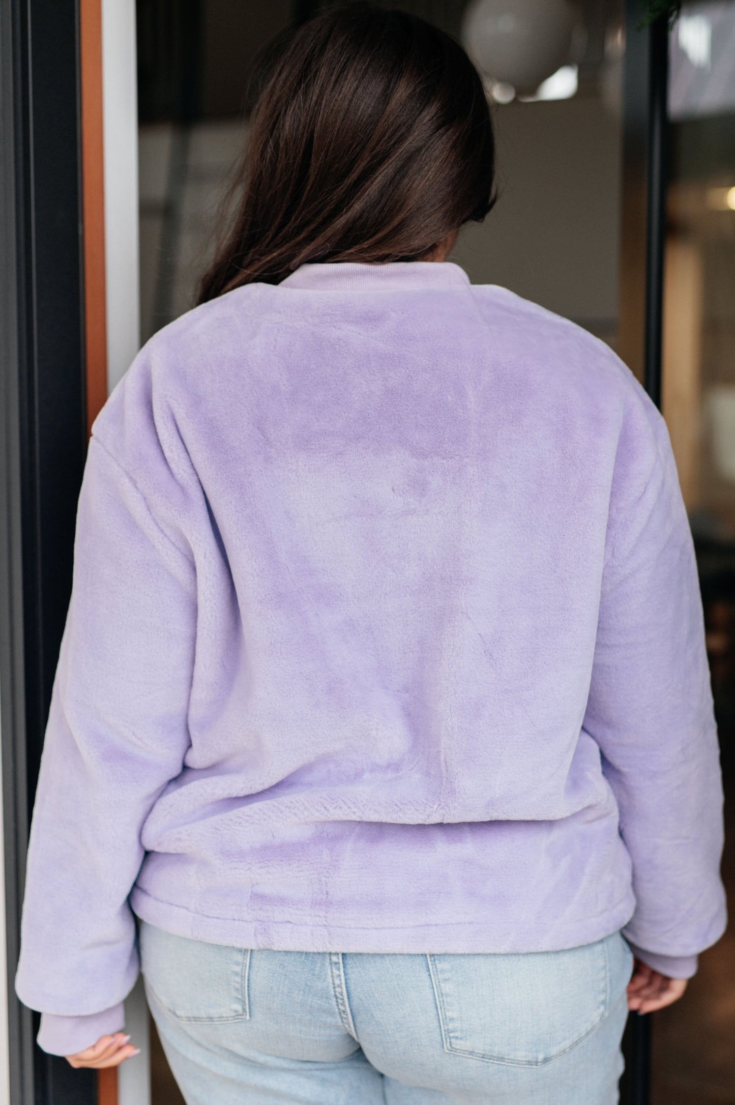 Person wearing a light purple fleece jacket with a blurred background