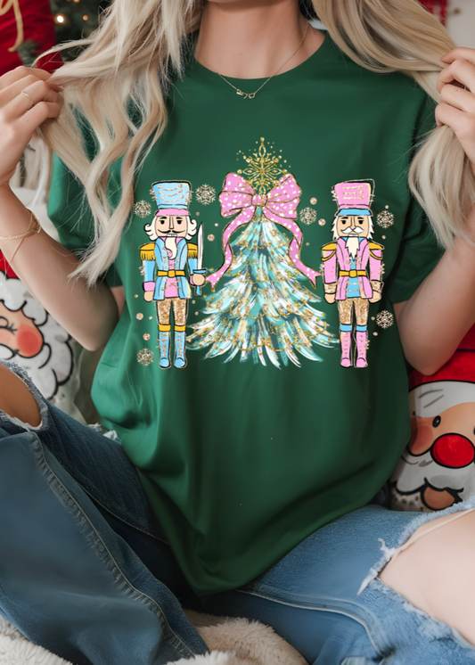 Person wearing a green t-shirt with Christmas-themed design featuring two nutcrackers and a tree.