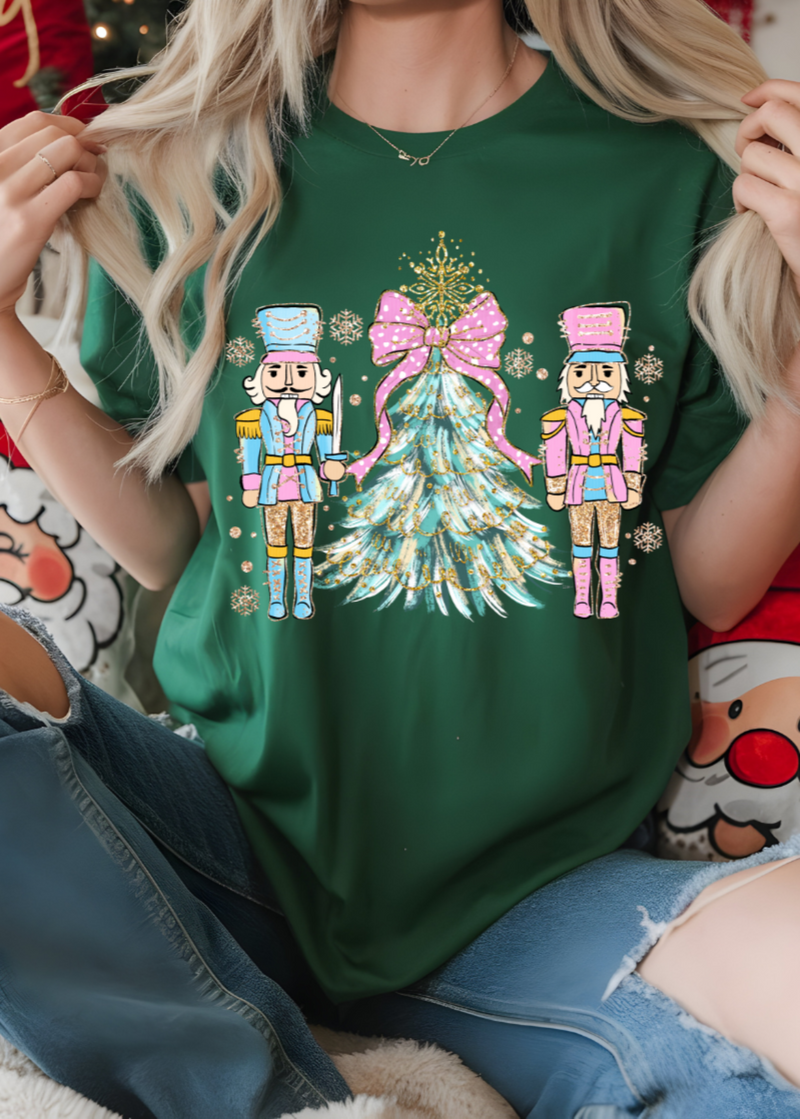 Person wearing a green t-shirt with Christmas-themed design featuring two nutcrackers and a tree.