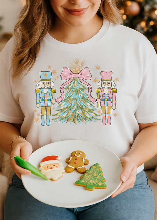 Person wearing a festive t-shirt with Christmas-themed graphics, holding a plate of cookies.