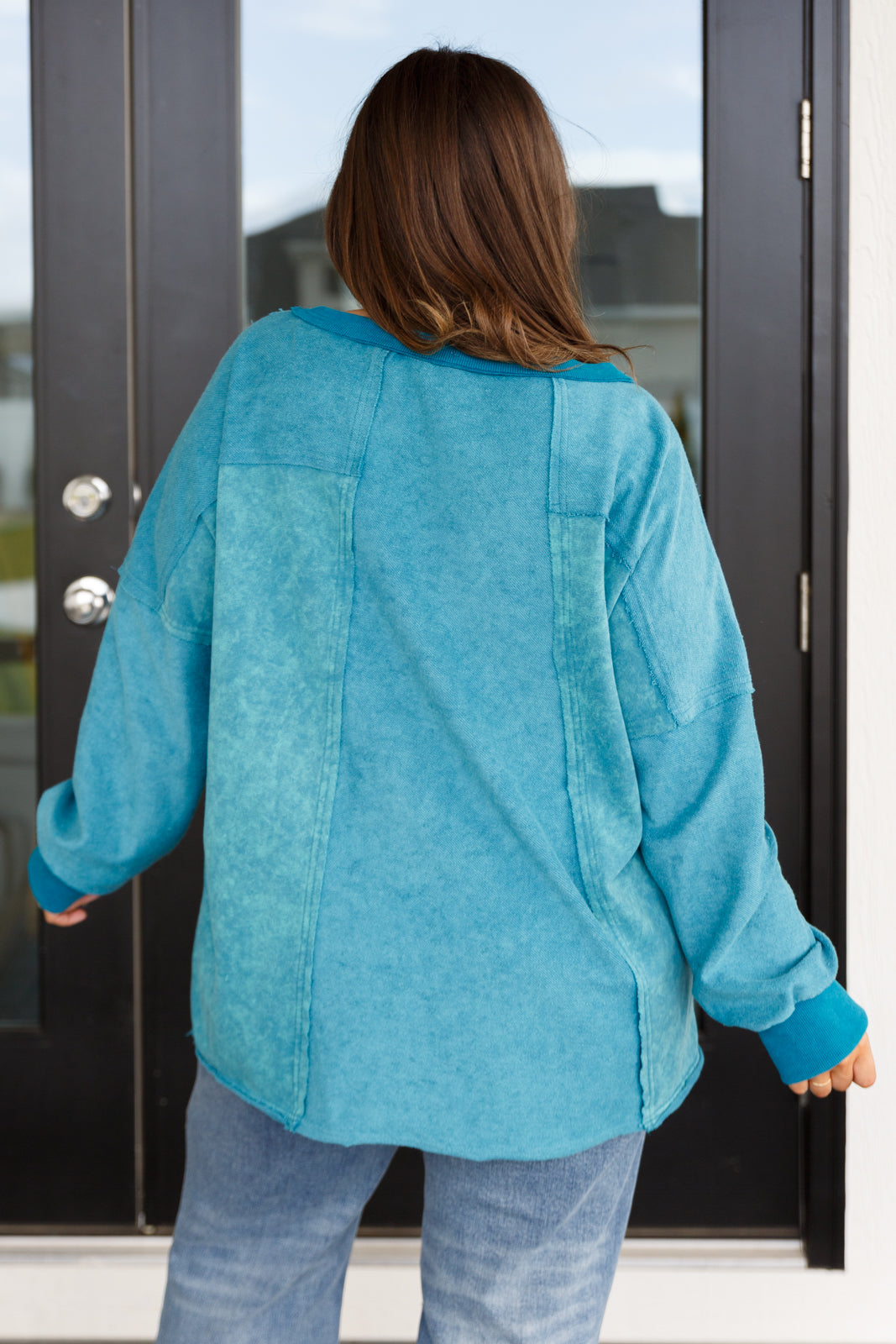 Person wearing a blue jacket standing in front of a glass door.