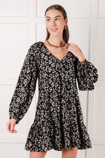 Woman wearing a black floral dress against a white background