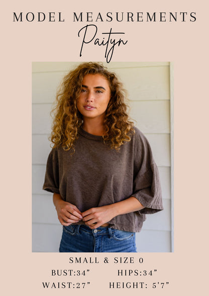 Woman wearing a brown oversized shirt and blue jeans with model measurements displayed.