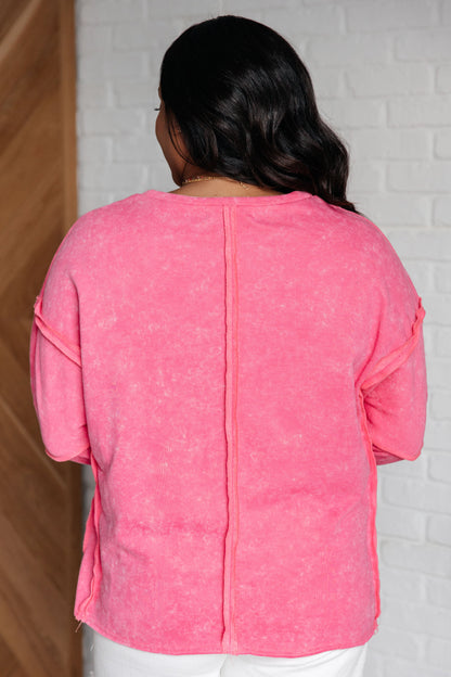Person wearing a pink top with a white brick wall background