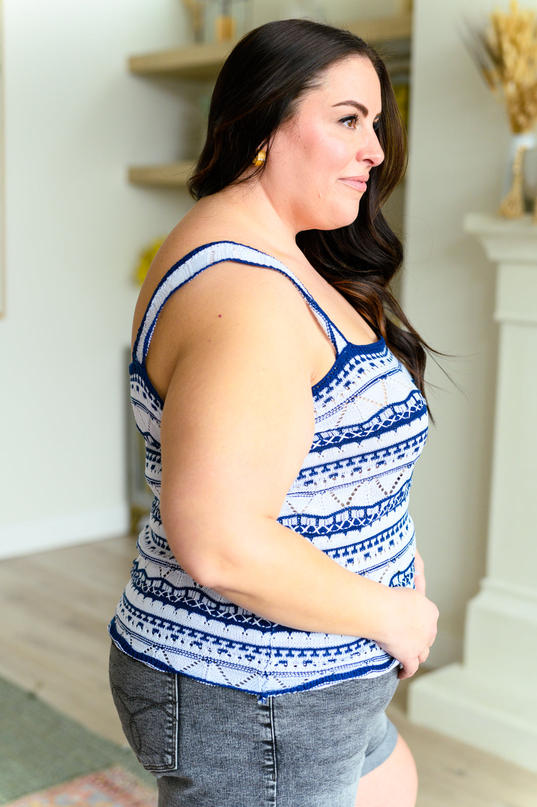 A woman wearing a blue and white geometric patterned tank top with scalloped trim.