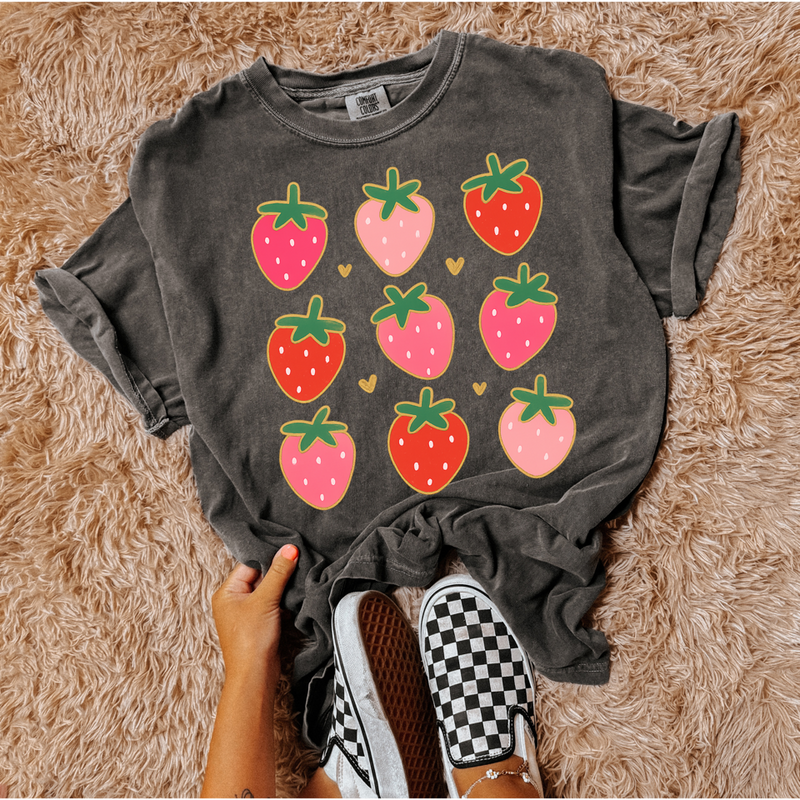 Dark gray t-shirt with strawberry pattern on a fluffy brown surface