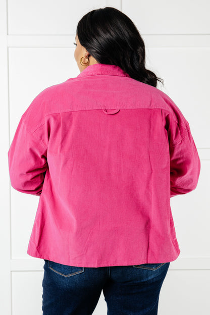 Person wearing a bright pink jacket against a white tiled wall