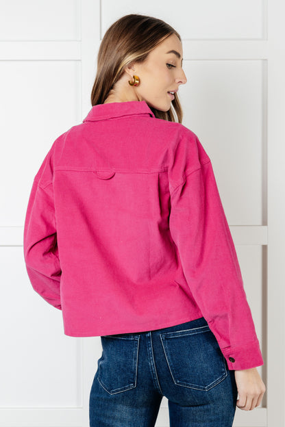 Person wearing a bright pink jacket and blue jeans against a white background