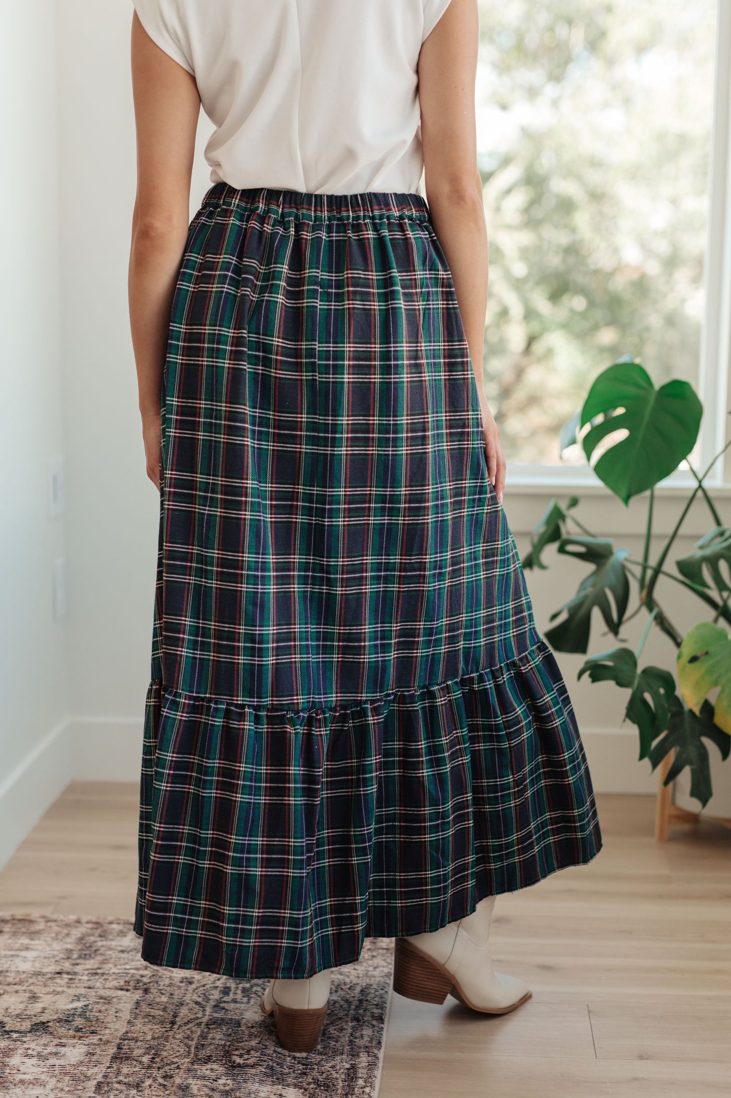 Person wearing a plaid skirt in a room with a plant