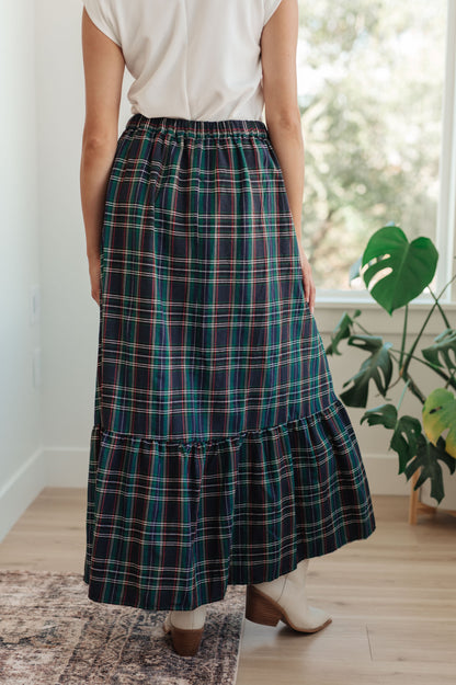 Person wearing a plaid skirt in a room with a plant