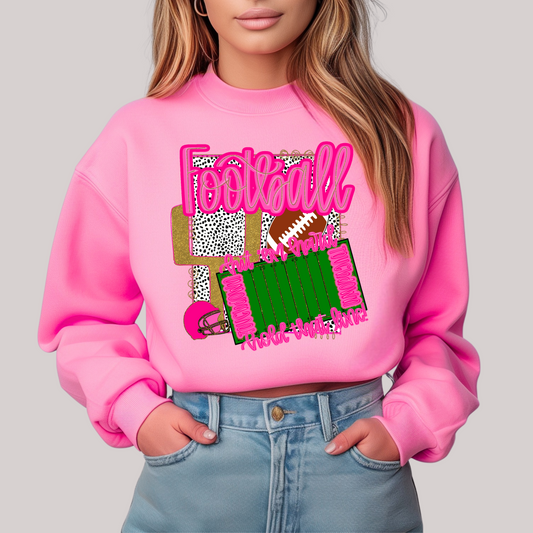 Person wearing a pink sweatshirt with football-themed graphics on a plain background