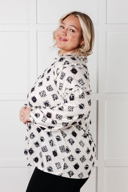 Woman wearing a patterned shirt against a white tiled wall