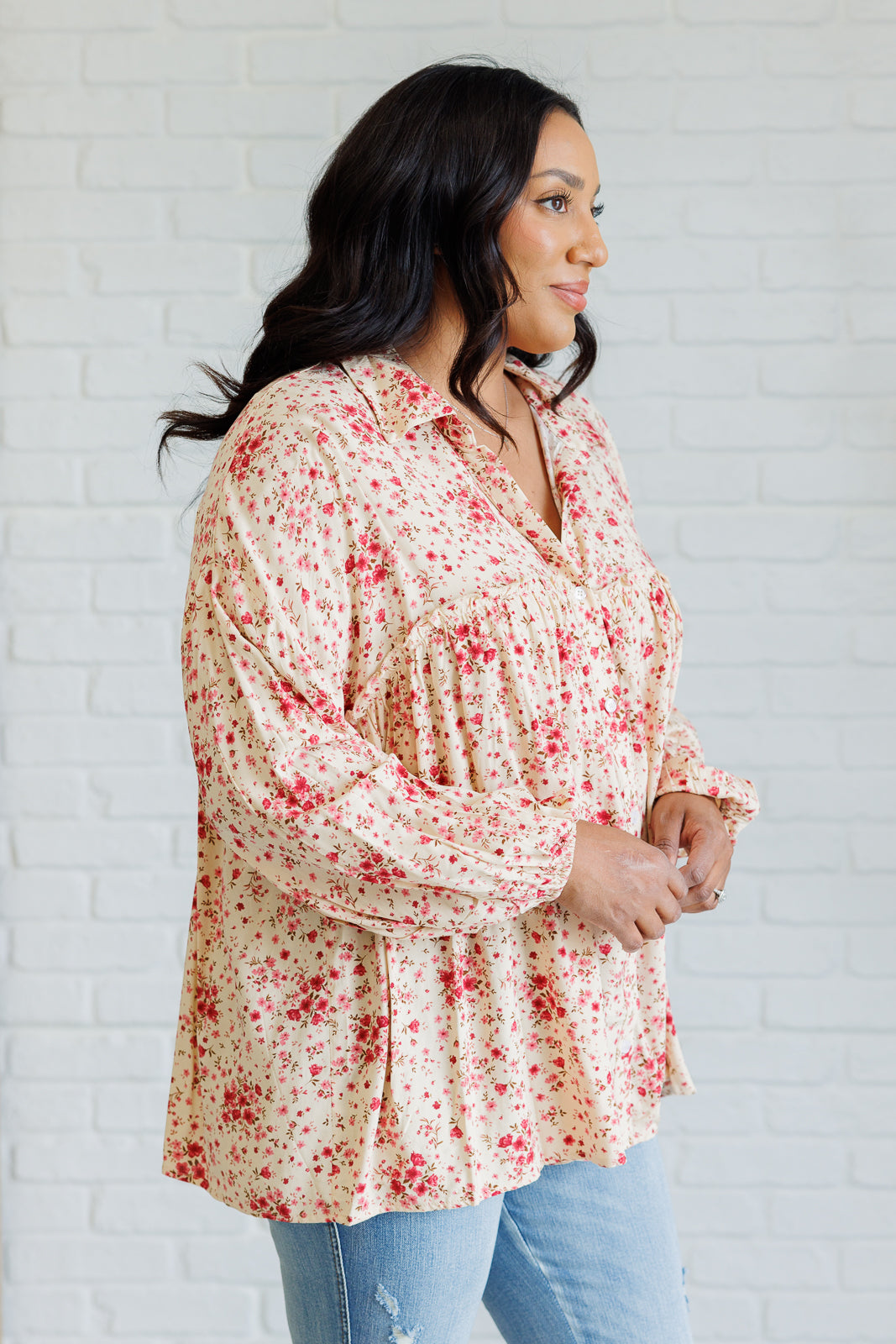 Woman wearing a floral blouse against a white brick wall