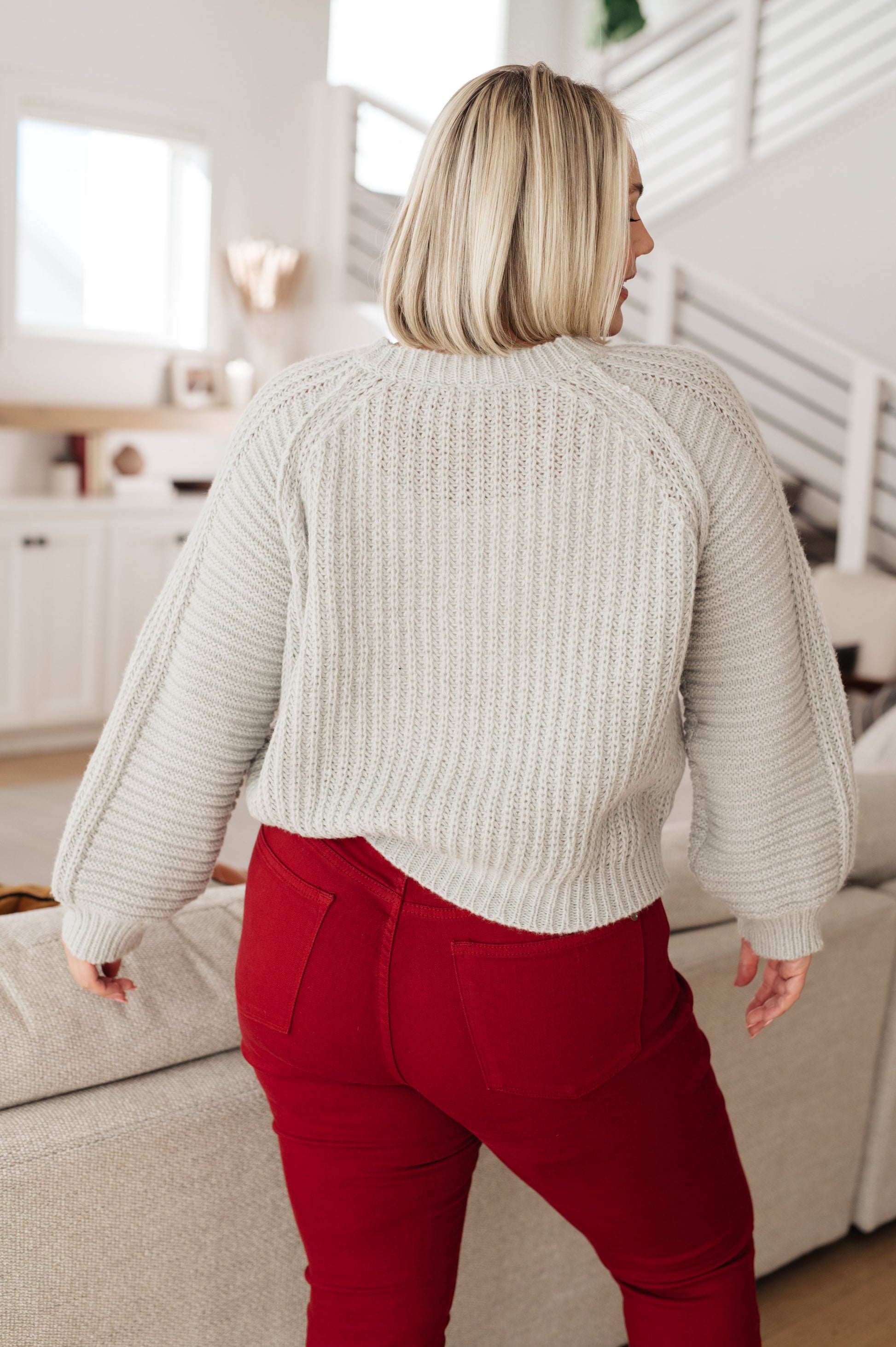 Person wearing a beige sweater and red pants in a living room setting