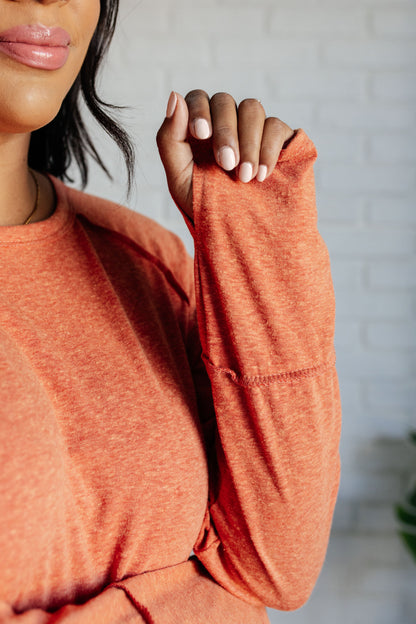 Person wearing an orange long-sleeve top with a blurred background
