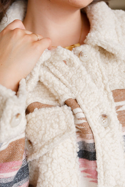 Close-up of a person wearing a plaid shirt with a white textured coat over it.