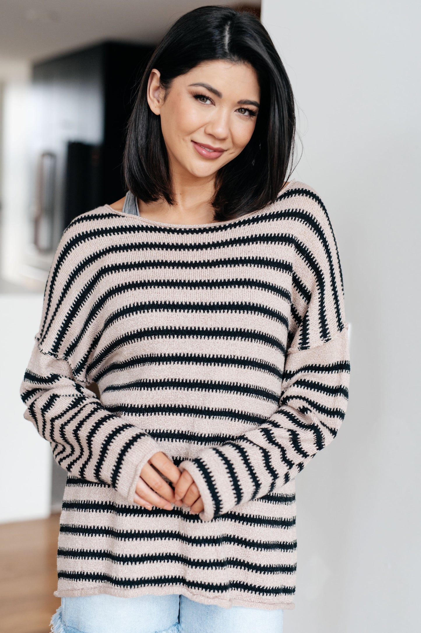Woman wearing a black and white striped sweater indoors.