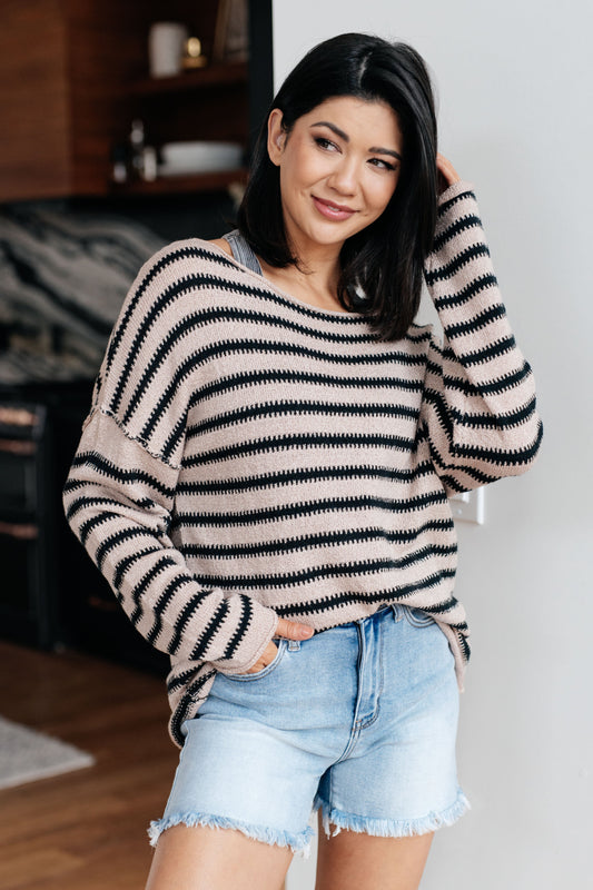 Woman wearing a striped sweater and denim shorts indoors.