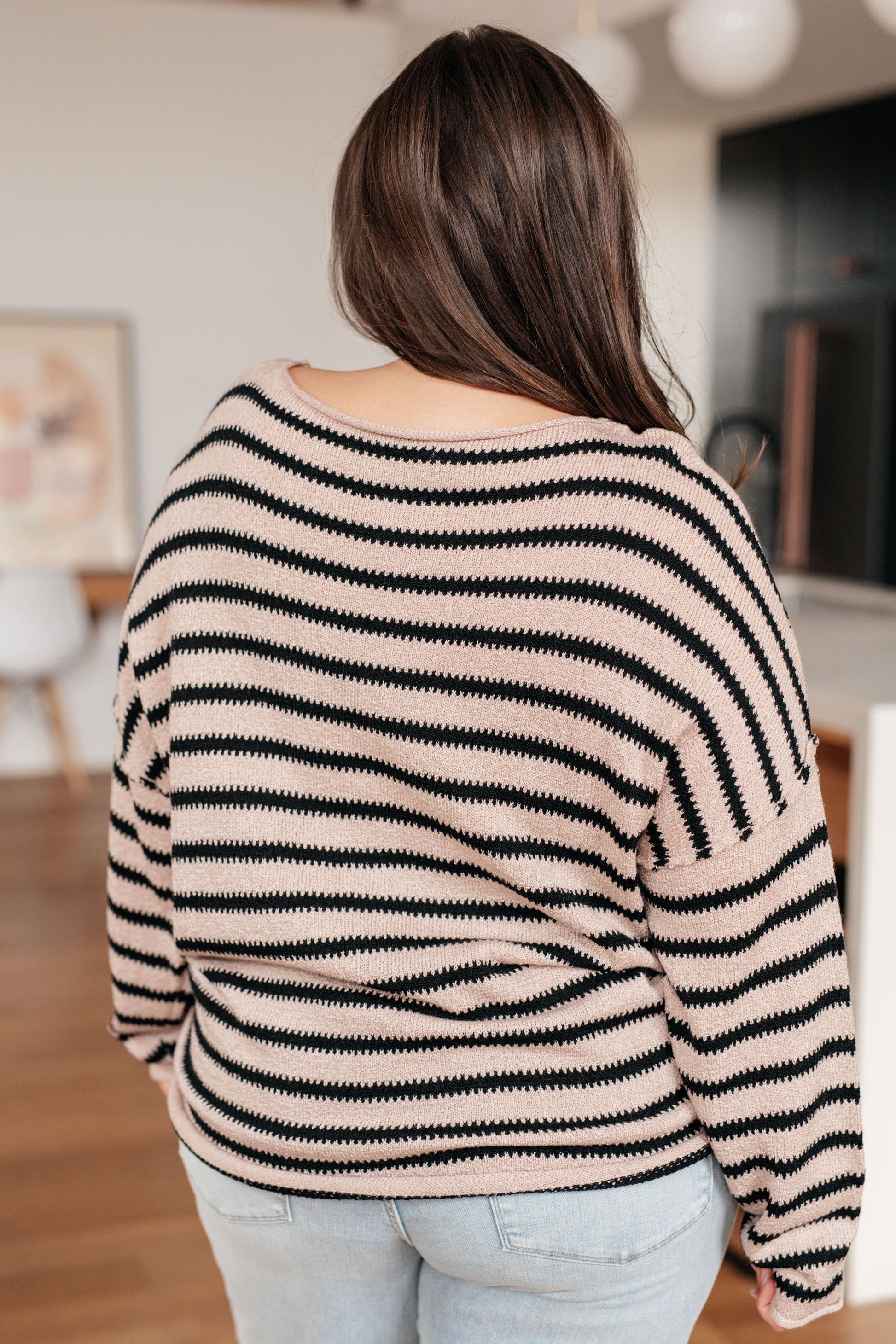 Person wearing a black and beige striped sweater in an indoor setting