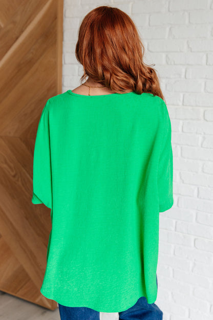 Person wearing a green top with a white brick wall background
