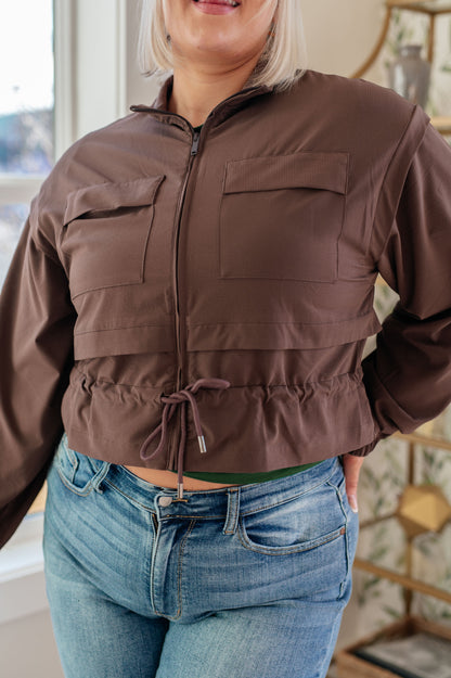 Person wearing a brown jacket and blue jeans indoors