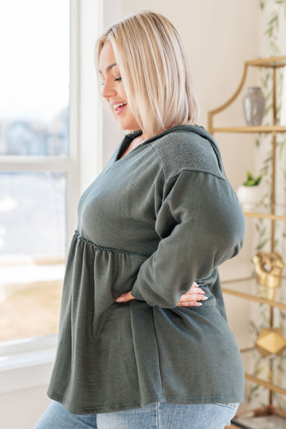 Woman wearing a green top in a room with a window and decorative items.
