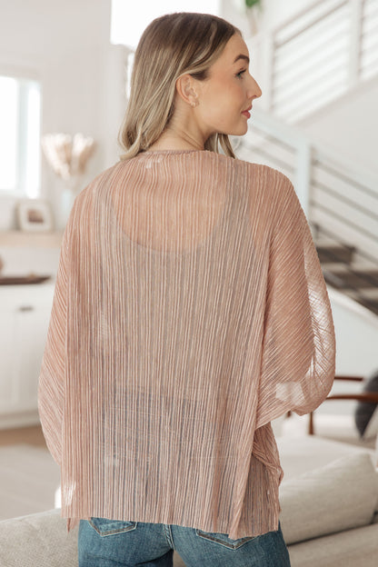 Woman wearing a sheer beige top in a bright room