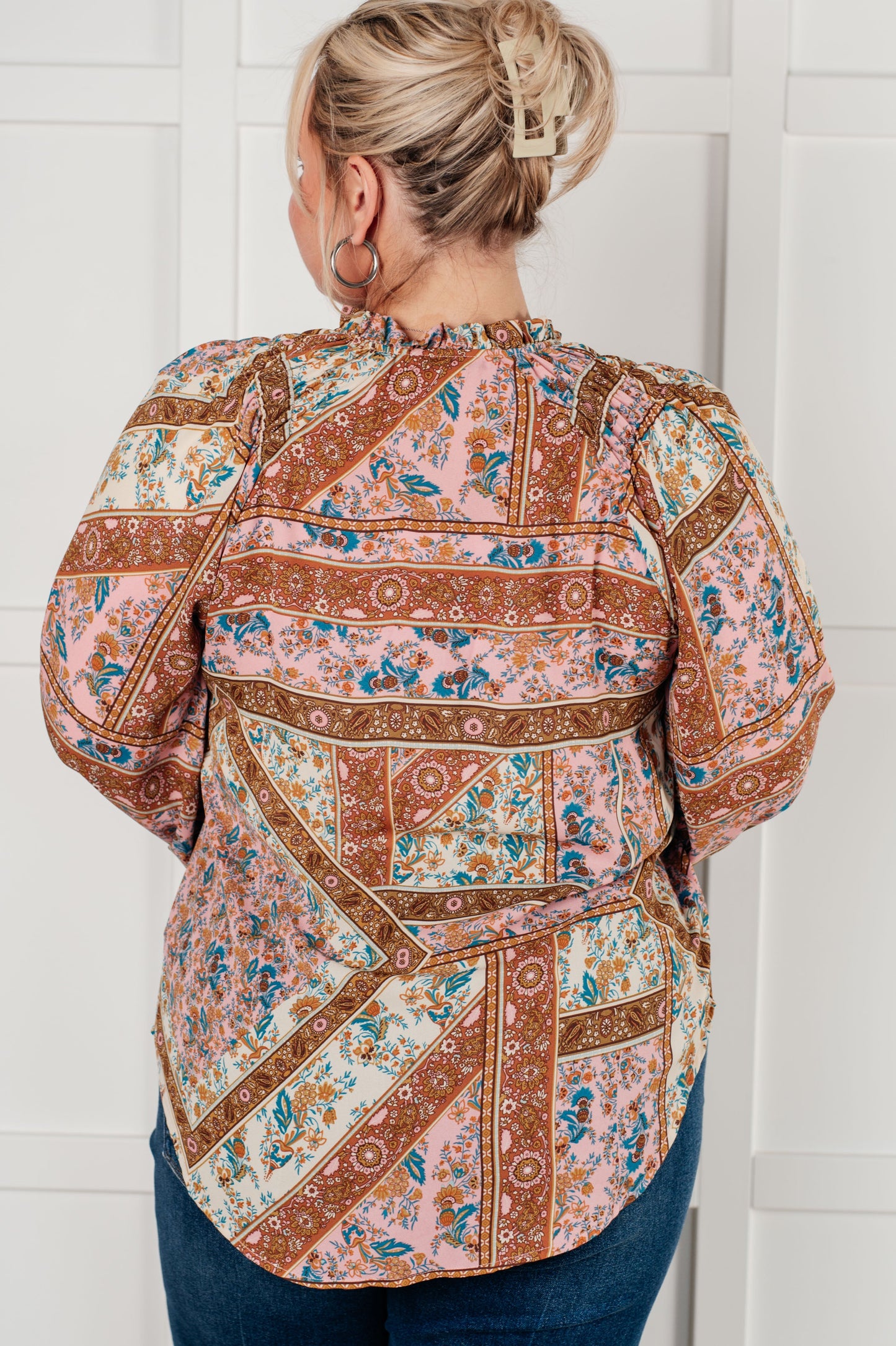 Person wearing a patterned blouse against a white wall