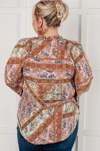 Person wearing a patterned blouse against a white wall