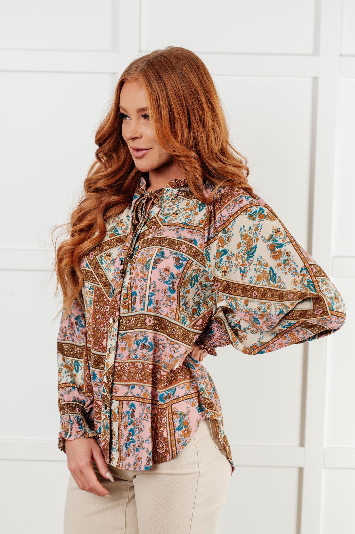 Woman wearing a patterned blouse against a white background