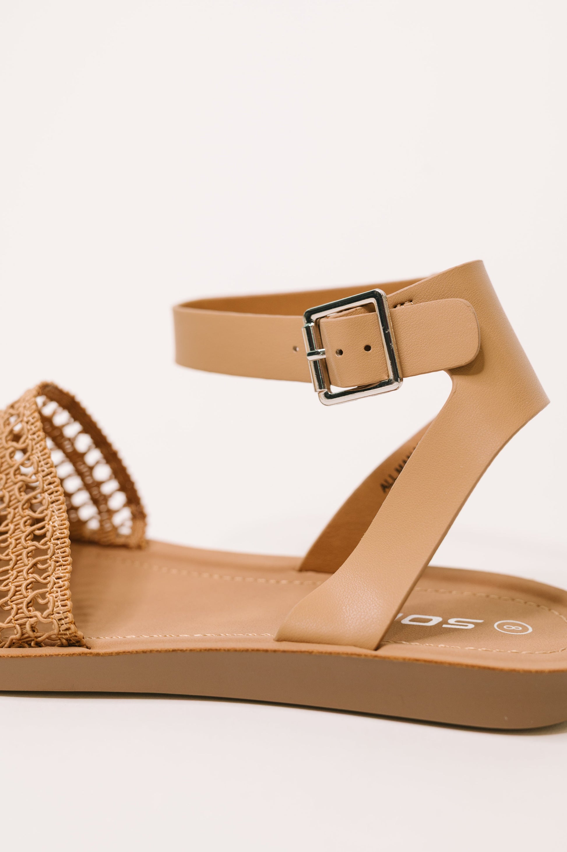Tan sandal with a woven strap on a white background