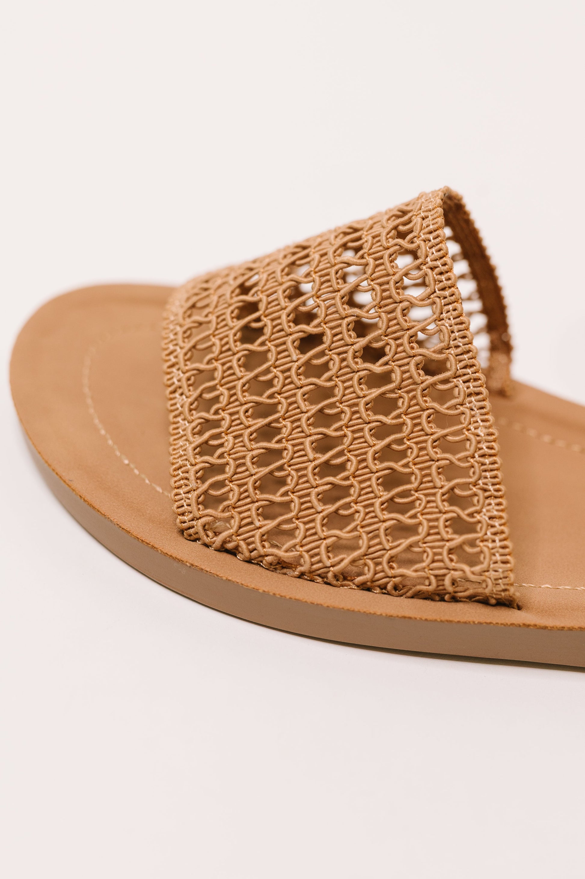 Brown sandal with woven strap on a white background
