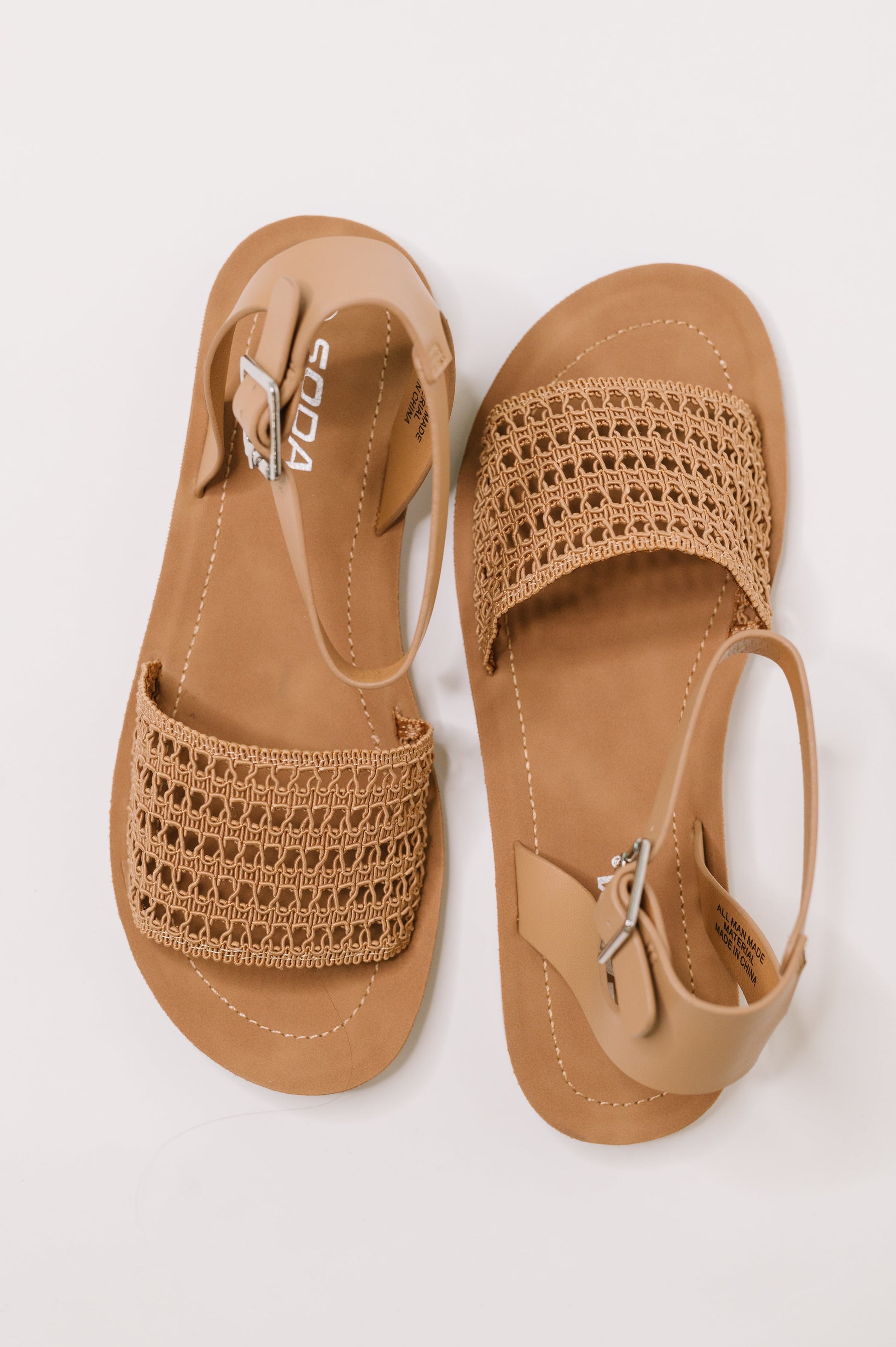 Pair of tan sandals with woven design on a white background