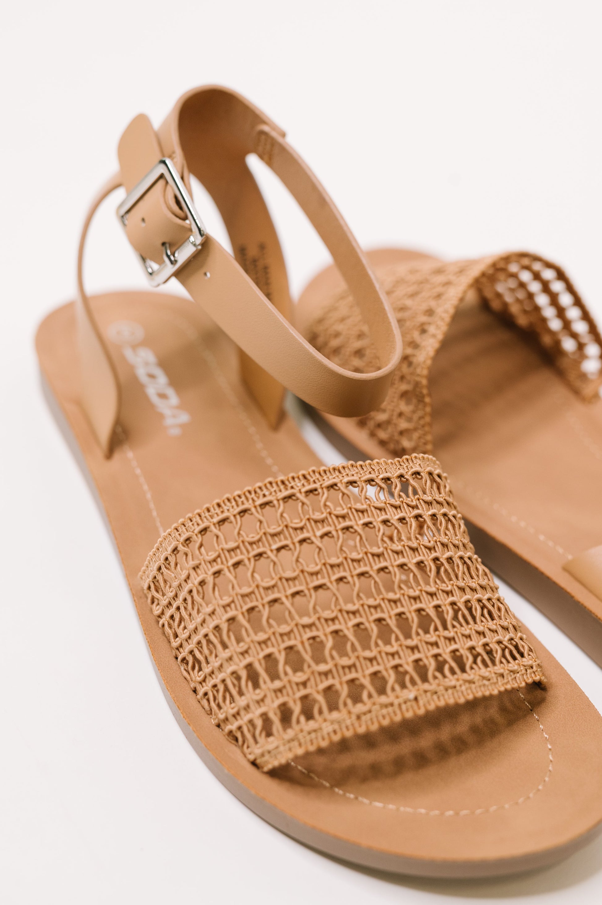 Tan sandal with woven strap on a white background