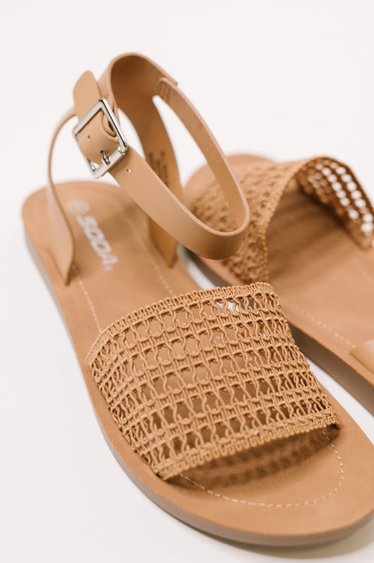 Tan sandal with woven strap on a white background