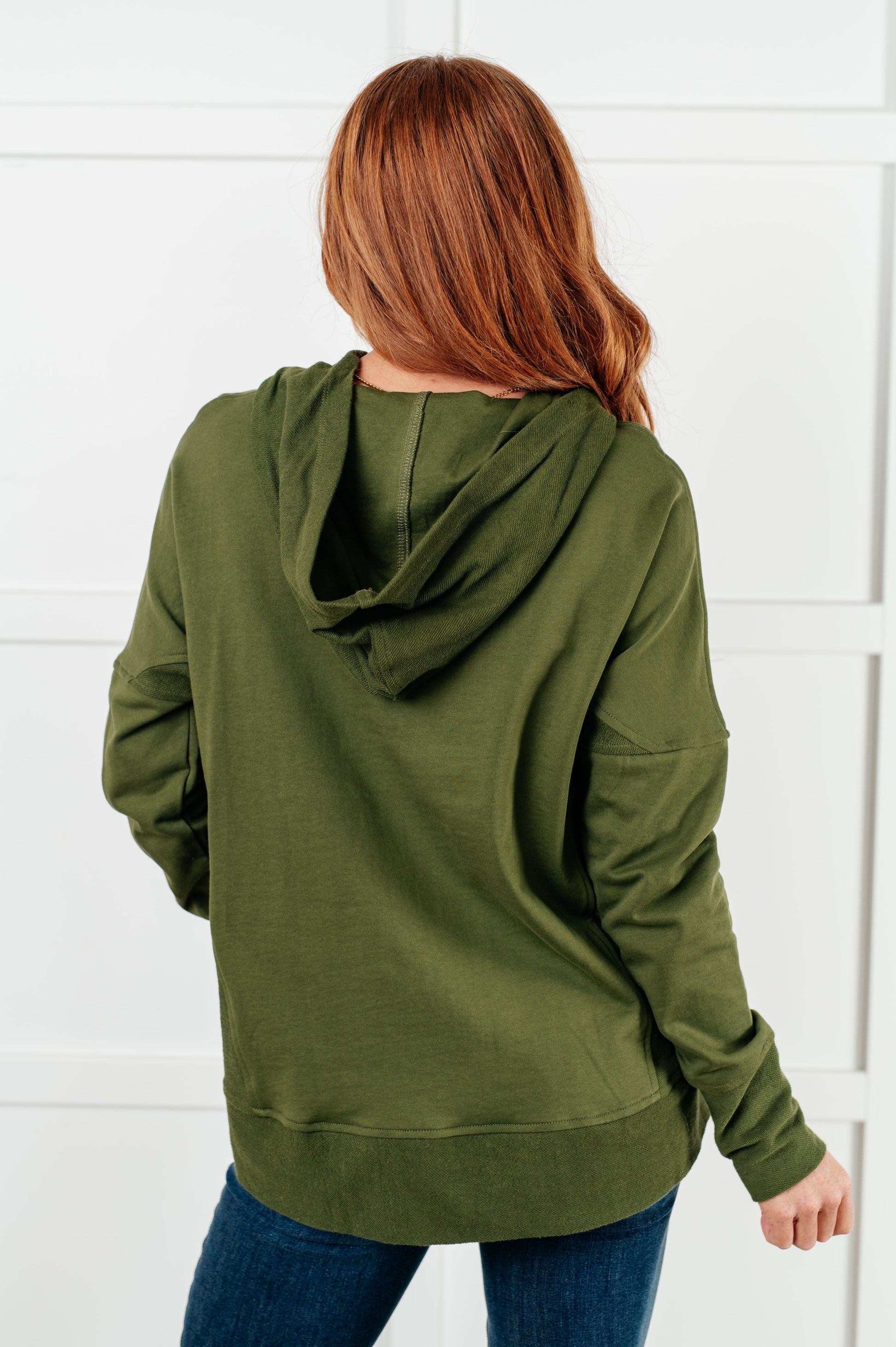 Person wearing an olive green hoodie with a white background